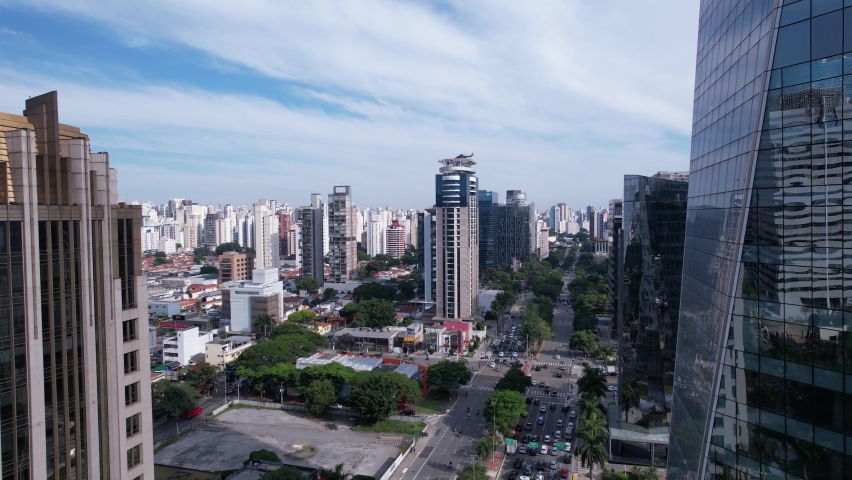 Aerial view of Avenida Brigadeiro Faria Lima, Itaim Bibi. Plane flying under commercial buildings. Helicopter taking off from a building.