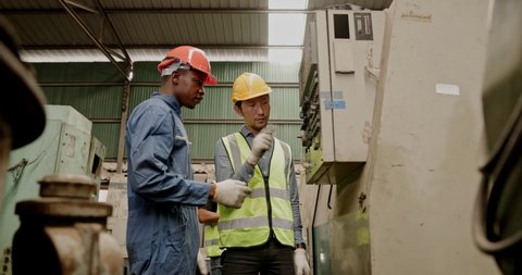 Group of machine technicians are profession inspect the electrical equipment in factory. Industrial plant engineers plan machine maintenance. African American workers work with Asian team Blue collar