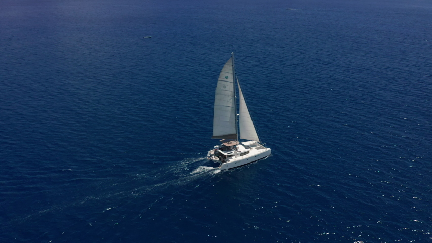 Aerial footage, rear view of luxury sailboat sailing on a deep blue sea with white wakes. Camera follow catamaran in blue ocean water Royalty-Free Stock Footage #1088719531