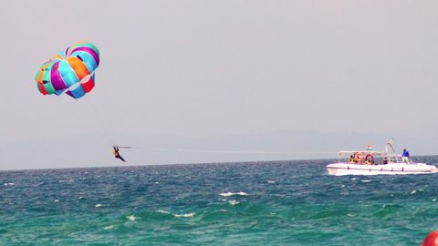 para sailing gliding person being dunked splashed in ocean sea water from sky and then lifting off into the sky in this adventure sports in havelock andaman island India