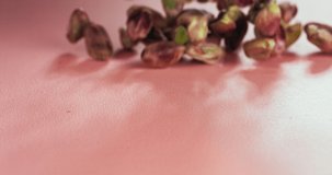Pistachio organic falling on pink surface. Bright macro shot. Super slow motion 1000fps