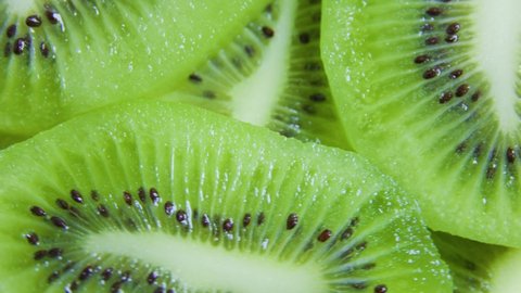 green citrus fruit slices of kiwi on rotating surface, close up top view, macro. Summer, tropical, natural, exotic and healthy food concept