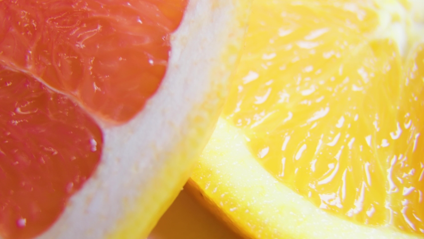 Close up many colorful fresh citrus fruit slices orange, grapefruit, on slow rotating surface, macro round fresh juicy sliced slices Of red citrus grapefruit rotate