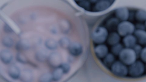 Bowl with yogurt and blueberries on table. Woman eating Blueberry yogurt with fresh blueberries. Healthy breakfast. Super food healthy eating vegetarian vegan food