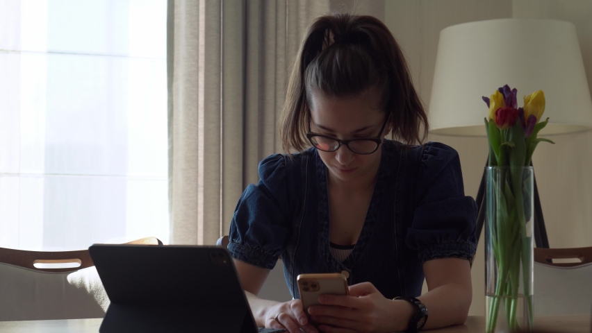 Authentic successful Young Woman Chatting On Phone In Living Room. Writing Searching Using IT. Happy smiling Lady Working On Smartphone Browsing Internet. Buisenes, Education, Technology Concept