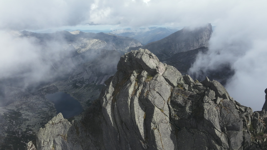 Huge stones, boulders and rocks shrouded in low clouds, Ergaki Natural Park, Russia. Summer foggy landscape high in the mountains with thick fog among the rocks. Wilderness hiking concept