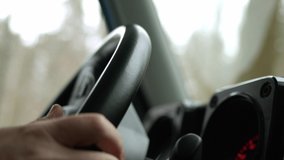 close up view of steering wheel that man is holding and driving in mountains and off-road on SUV, shaky natural video handheld because of road rough. Rack focus.