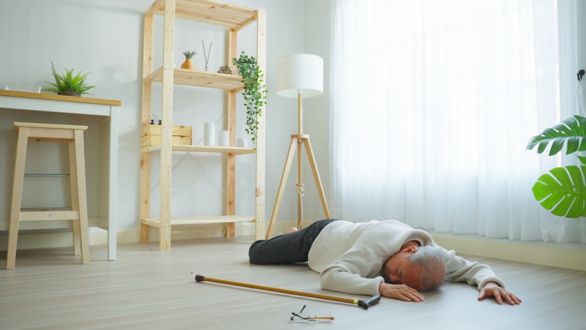 Asian young son helping senior male from falling on the ground at home. Elderly older mature grandfather having an accident after doing physical therapy then rescued by attractive man in living room. Royalty-Free Stock Footage #1088728499
