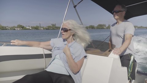 Married couple on boat cruises along the ocean on a bright sunny day