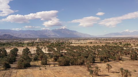 Coachella Valley California surrounded by mountains. Drone flying over date palms.
