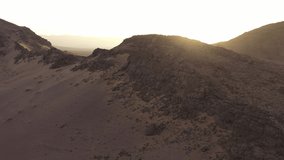 Sunlight illuminating valley behind rocky desert mountains, Zagora in Morocco. Aerial drone view