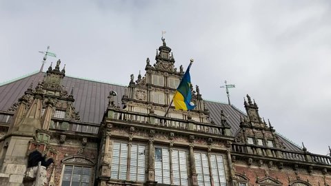 Bremen , Bremen , Germany - 03 26 2022: Ukrainian Flag flying on Bremen Town hall, pan to Cathedral