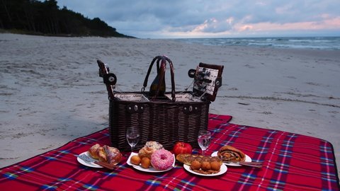 Picnic basket at the beach. Cozy and classy picnic on the sand by the sea. Summer holidays and spring break concept. Romantic dinner for couple and friends.