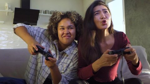 Two girls play video games with joysticks at home. Home entertainment with friends