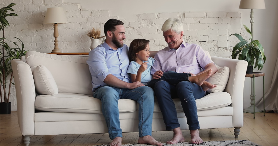 Communication, good strong relations between diverse generation relative people, multigenerational family ties concept. 50s granddad his son and grandson spend time together sit on sofa and talking Royalty-Free Stock Footage #1088739623
