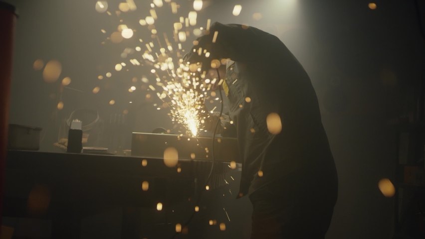 Industrial worker cutting metal with many sharp sparks. Male using special tool for cutting metal at workshop. Sparks flying from metal processing. Slow motion. 4K video. Shot on RED | Shutterstock HD Video #1088739649