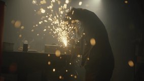 Industrial worker cutting metal with many sharp sparks. Male using special tool for cutting metal at workshop. Sparks flying from metal processing. Slow motion. 4K video. Shot on RED