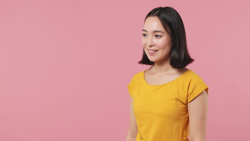 Fun promoter young woman of Asian ethnicity 20s wears yellow t-shirt point index finger aside scream in megaphone announces sale Hurry up isolated on plain pastel light pink background studio portrait Royalty-Free Stock Footage #1088741419