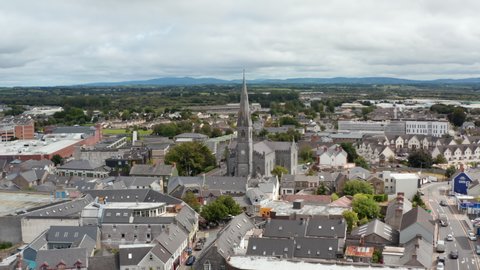 Slide and pan aerial footage of historic stone cathedral surrounded by town development. Ennis, Ireland