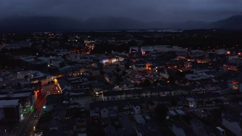 Aerial panoramic footage of town centre. Illuminated colour house facades. Lake and mountains in backgrounds. Killarney, Ireland