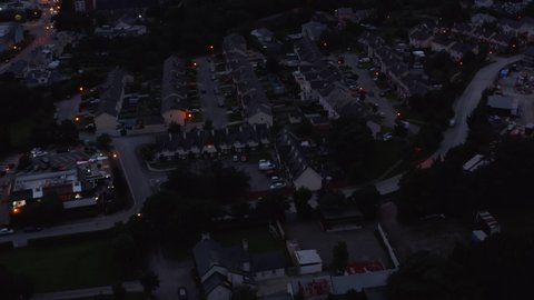 High angle footage of rows on family houses in residential urban borough. Tilt up reveal of panoramic view of town and lake in background. Killarney, Ireland