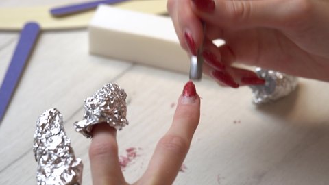 Removing old nail polish with a scraper. Selfmade manicure service. Manicurist paints nails with pink gel polish. Manicured pink nails. Nail polish application.