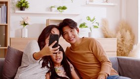 Asian family are calling on smartphone. All happy using cellphone for video call, smiling family having fun greetings online with making video call communication through application together.