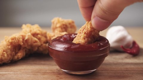 Dipping Chicken Wing into dip sauce on a table. Fast Food, Appetizer, Junk food and unhealthy eating concept