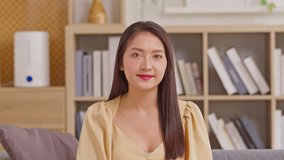 Camera first view Beautiful Asian young woman talking and introducing myself via video conference call smile at home. Portrait happy teacher coach looking at camera online class or vlogger recording