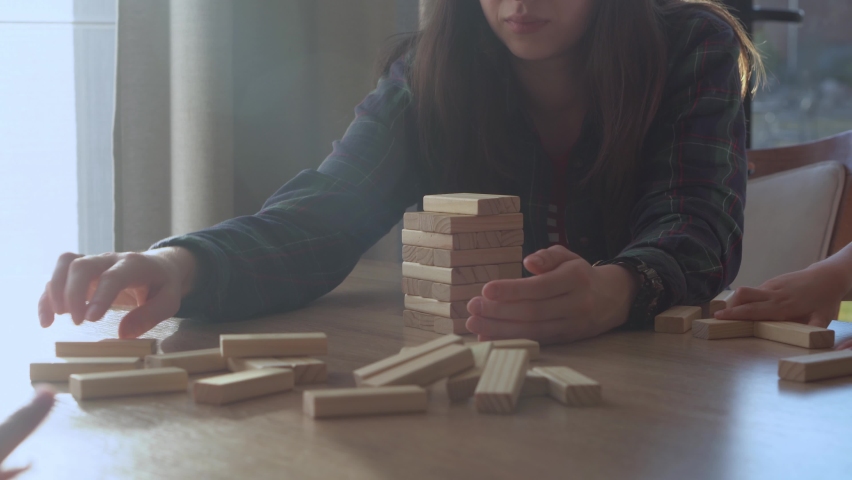 Small Kids Children playing tiny jenga with her parents at table, jenga tower falls apart, Family have great time together play game at home in sunny room Day, happy childhood, Friendship concept