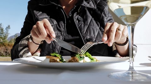 Woman Eating in a Luxury Restaurant Seared scallops with Turnip Greens and Buffalo Stracciatella Cheese and Aromatic Bread in a Sunny Day in Switzerland.