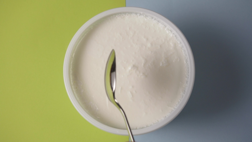Bowl of sour cream with spoon on green, blue background, greek yogurt | Shutterstock HD Video #1088746363