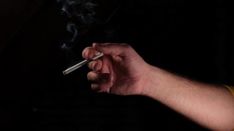 hand with a smoking cigarette on a black background