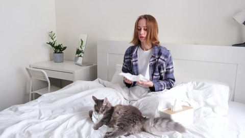 A young woman sneezes from allergies to her cat. The concept of seasonal illness and asthma.