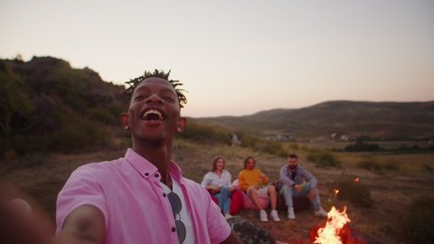 African american man takes selfie with his friends at camping, they laughing and smiling, hold alcoholic cocktails and drinks their hands. A man takes pictures of himself friends in outdoor स्टॉक वीडियो