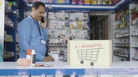 focus on box with e-shopping sign board, pharmacist busy taking order on mobile phone at medical store - concept of successful online business, epharmacy