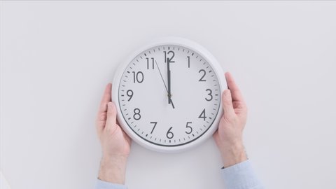Mans hands put clock on table. White watch on white background top view. Twelve o'clock. 12 hours.