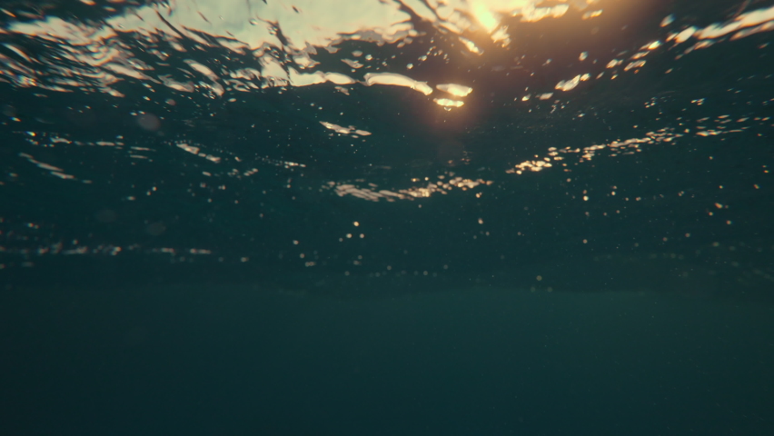 SLOW MOTION, UNDERWATER: Massive turquoise barrel wave breaks over the camera on a sunny summer evening in the scenic Caribbean. Cinematic view of a crystal clear breaking ocean wave at golden sunset.