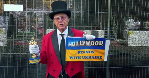 LOS ANGELES, CALIFORNIA, USA - MARCH 26, 2022: Senior man in red suit and hat supports Ukraine against Russian invasion war prior to Oscar Academy Award Nomination at Hollywood and Highland in LA