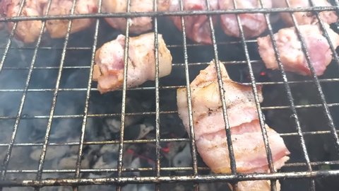 Fresh salmon fish and bacon meat on on barbecue grill grate. Barbecue cooking on fried smoked grill. Healthy lunch roast bbq on countryside campfire. Camping food, picnic, weekend resting concept