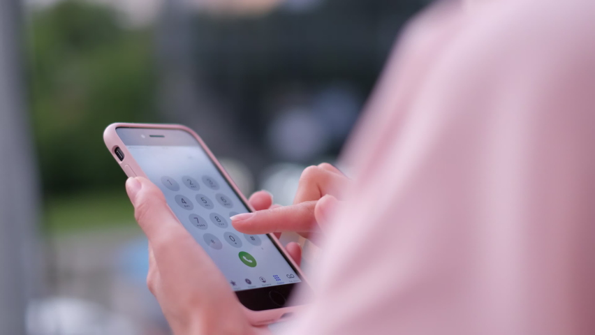 A young girl is dressed in a pink jacket, she uses a smartphone for notifications. Woman wearing sunglasses. Slow motion
