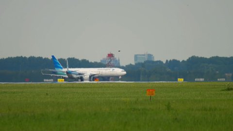 AMSTERDAM, THE NETHERLANDS - JULY 26, 2017: Long shot side view, Boeing 777 of Garuda Indonesia accelerating and taking off at Schiphol Airport, Amsterdam. Garuda Indonesia is the national airline of