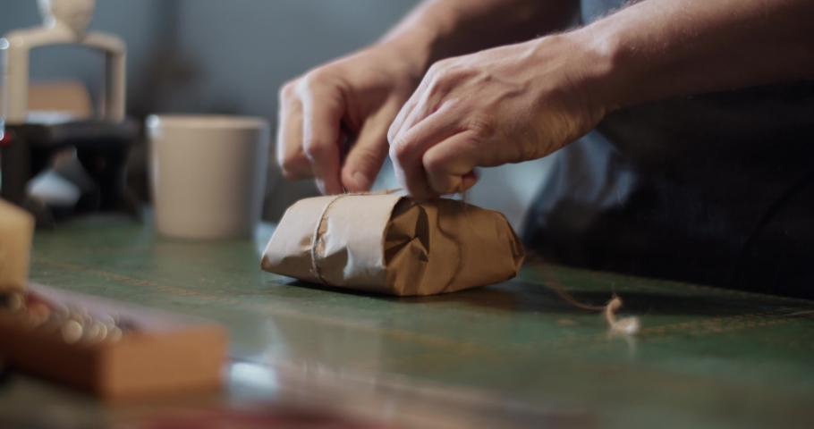Male artisan wrapping parcel on table