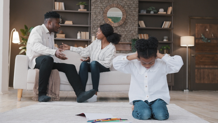 Sad little african daughter child kid girl closing ears upset at parents fighting arguing quarrel conflict at home stressed baby suffer from psychological trauma problem by divorce domestic violence | Shutterstock HD Video #1088764385