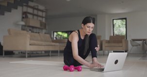 Fitness instructor during a coronavirus pandemic prepare a laptop and exercise equipment to perform online training at home