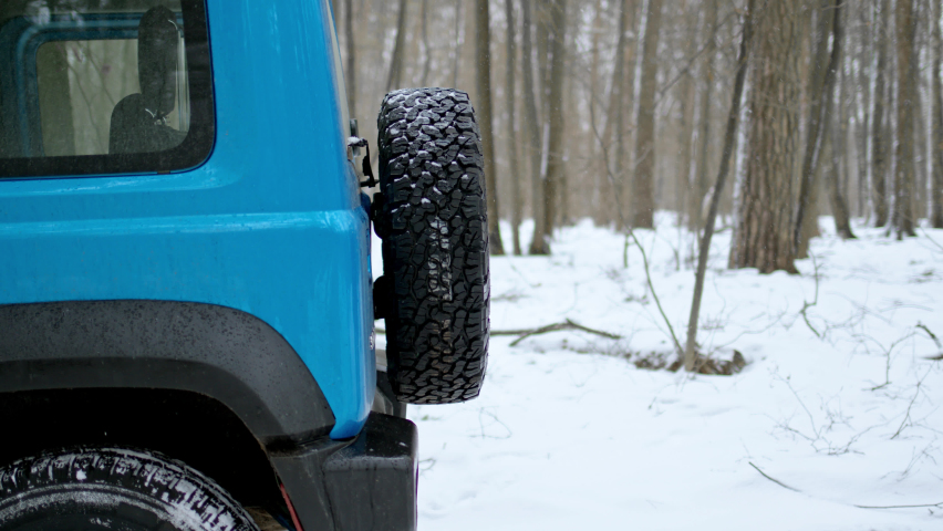 blogger with phone in his hands open trunk of small SUV. man record process of opening back door of blue car with spare tire on door.