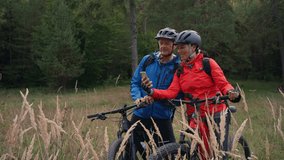Senior couple bikers using smartphone outdoors in forest in autumn day. - Powered by Shutterstock - Get 15% off with code: PIKWIZARD15