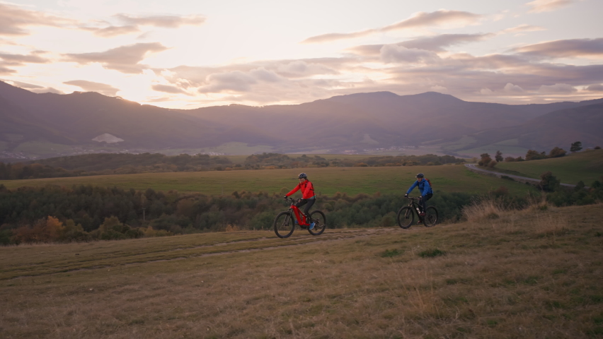 Side view of active senior couple riding bikes outdoors in forest in autumn day.