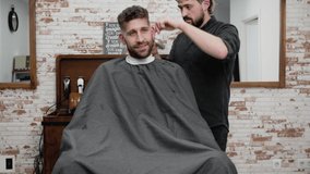 Man barber cutting hair of male client with clipper at barber shop. Hairstyling process. High quality 4k footage