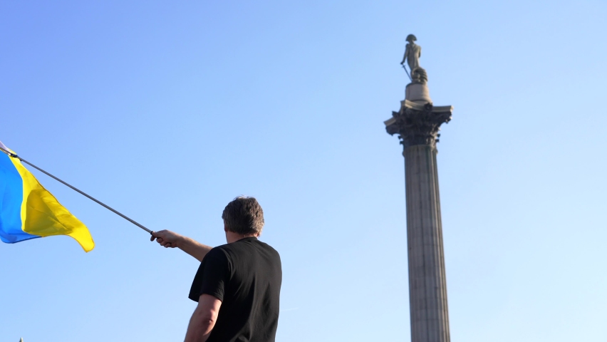 London stands with Ukraine, protester waving the Ukrainian flag in Trafalgar Square in London during protest against war with Russia